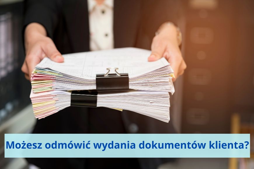 Dwie dłonie trzymają stos dokumentów spięte grubymi spinaczami do papieru