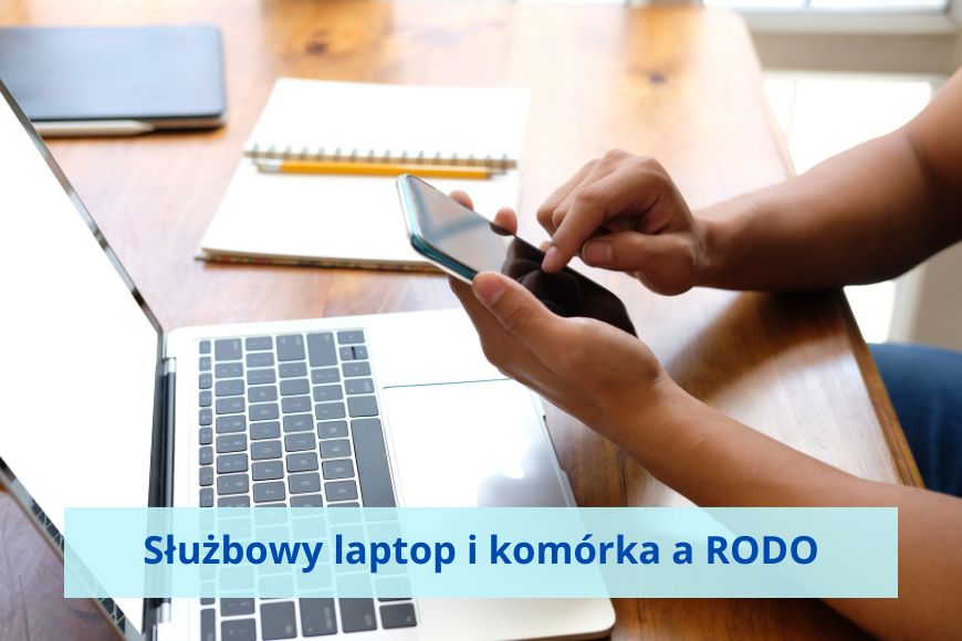 Na stole leży laptop i otwarty notes, ręce wpisują coś na komórce.